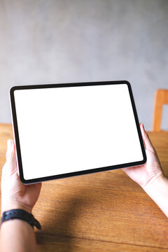 Vertical mockup image of a woman holding digital tablet with blank white desktop screen
