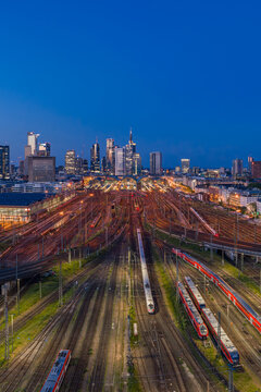 Frankfurt am Main, Germany - 08 May 2026: Aerial view of Frankfurt Hauptbahnhof with its extensive railway tracks and trains, set against the illuminated skyline of Frankfurt at dusk.