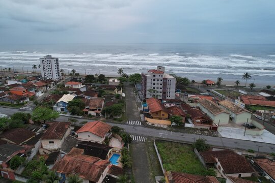 Aerial view of the coastal town of Mongagua featuring residential buildings with red-tiled roofs and the Atlantic Ocean in the background in Mongagua, State of Sao Paulo, Brazil.