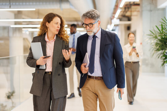 Businesswoman and businessman discuss strategy while walking in office