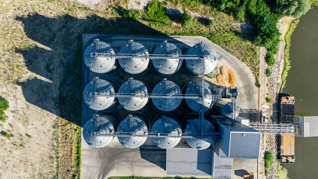 Aerial view of industrial grain silos arranged in a grid pattern with metal roofs and connecting walkways located near a riverbank in Beocin, Vojvodina, Serbia.