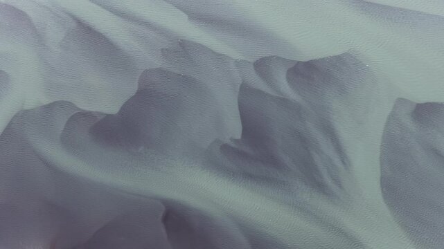 Aerial view of intricate glacial river patterns and sediment deposits flowing through the volcanic landscape of Iceland.