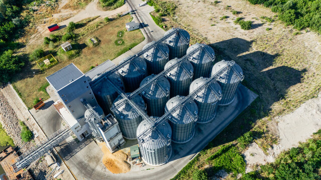 Aerial view of a grain silo facility with multiple metal storage tanks and a processing building surrounded by greenery in Beocin, Vojvodina, Serbia.