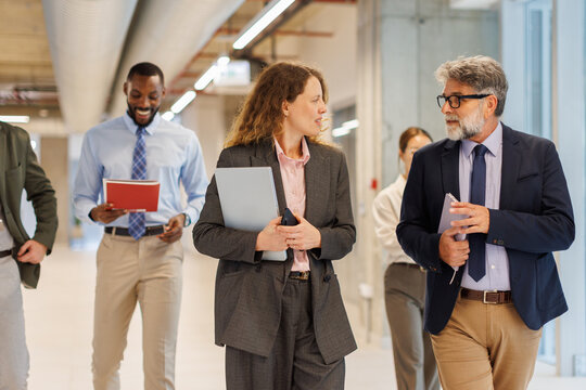 Businesswoman and businessman walk and talk in the office corridor