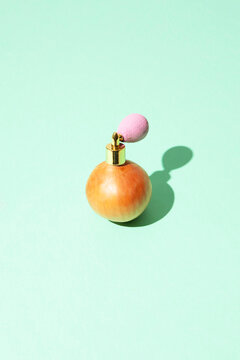 An onion features a pink perfume atomizer on a green background