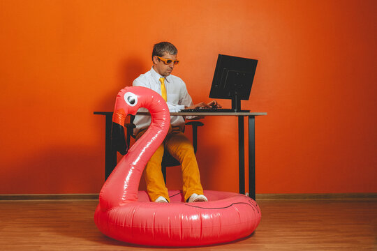Man in office works on computer inside pink inflatable flamingo