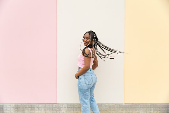 Casual woman smiles and turns by a pastel wall outdoors