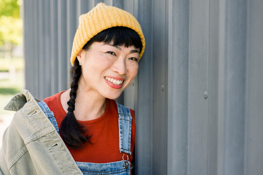 Portrait of laughing woman in casual urban outfit with hat outdoors