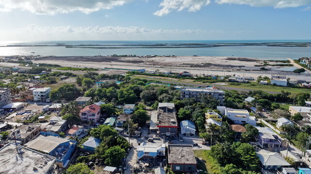 Aerial view of the coastal town of San Pedro on Ambergris Caye with colorful buildings, lush vegetation, and the Caribbean Sea in the background San Pedro, Corozal District, Belize.