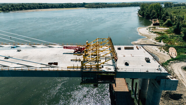 Aerial view of the bridge construction over the Danube river featuring a yellow steel framework and concrete deck in Sremski Karlovci, Vojvodina, Serbia.