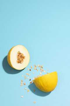 A yellow honeydew melon spills wood chips on a blue background