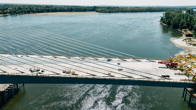 Aerial view of a modern cable-stayed bridge under construction over the Danube river with steel cables and concrete deck in Sremski Karlovci, Vojvodina, Serbia.