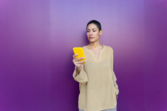 Female business professional uses smartphone on purple background