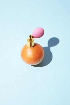 An onion wears a pink perfume atomizer on a blue background