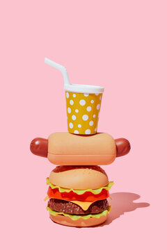 Plastic toy fast food stacks on a pink background