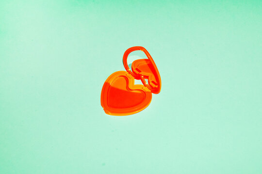 Red heart shaped makeup mirror lies on a green background