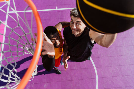 Men play streetball on a purple outdoor basketball court