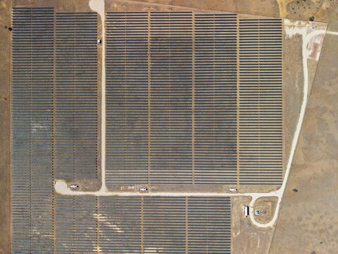 Aerial view of the Camden Park solar farm with rows of photovoltaic panels arranged in a grid pattern across the arid landscape in Longreach, Queensland, Australia.