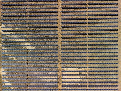 Aerial view of Camden Park solar farm with rows of photovoltaic panels installed on arid ground in Longreach, Queensland, Australia.