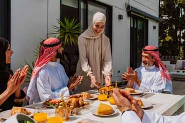 Fototapeta premium Muslim family members enjoying a traditional meal outdoors