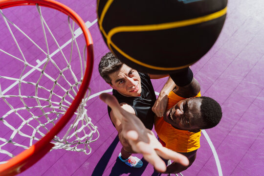 Men play a competitive basketball game on an outdoor court
