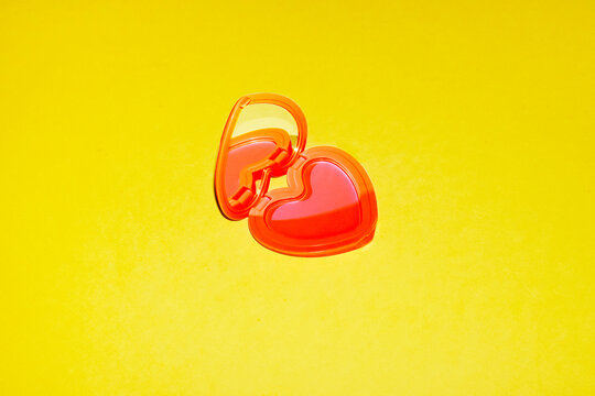 A red heart shape mirror lies on a yellow background