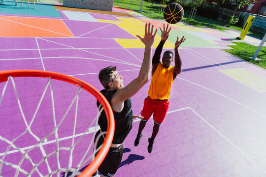 Athletes play a basketball game on a colorful outdoor court