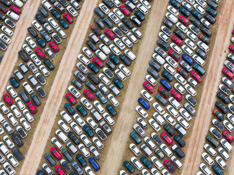 Aerial view of rows of parked cars in a car forwarding lot with various colors and models arranged in neat lines in Poland.