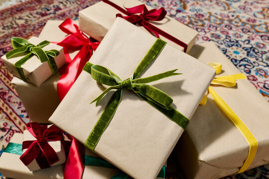 A stack of wrapped holiday gifts rests on a Persian carpet