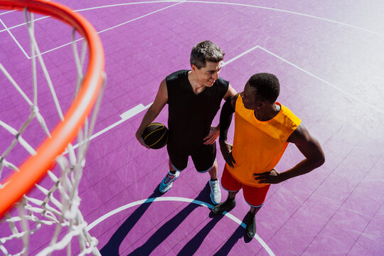 A man with a basketball talks to his teammate on the court