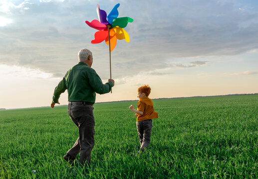 Grandfather and grandson walk in the field with a colorful chopper