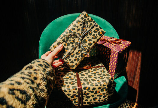 Female hand taking a stylish leopard print gift from a green armchair