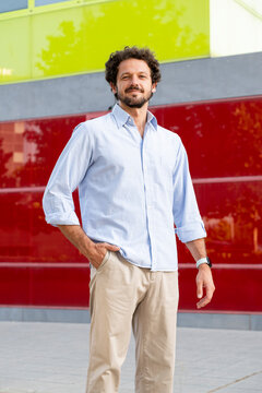 Confident young entrepreneur stands outdoors by a colored wall