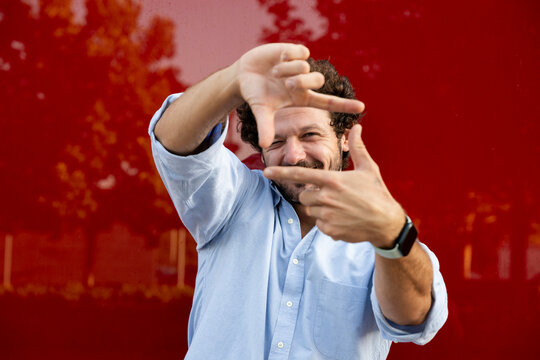 Smiling businessman frames his vision with hands outdoors