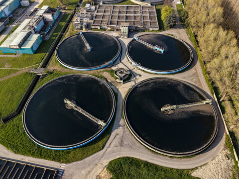 Aerial view of the wastewater treatment facility in Peschiera Borromeo featuring large circular sedimentation tanks and water management infrastructure in Milan, Lombardy, Italy.