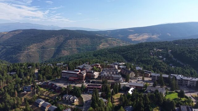 Aerial view of La Molina mountain resort village surrounded by pine forests and ski slopes in the Catalan Pyrenees, Spain, on a clear summer day