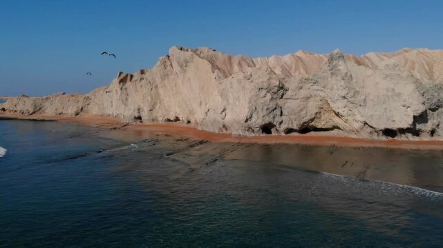 Aerial view of Makran Coastal Highway cliffs with rugged rock formations and a sandy beach along the coastline in Balochistan, Pakistan.