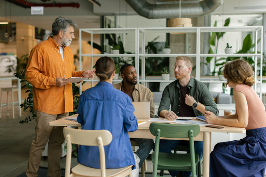 A manager leads a brainstorming meeting in a modern coworking office