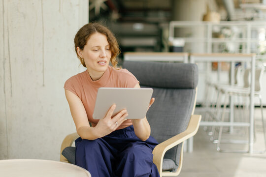 A smiling entrepreneur uses a digital device in a modern office