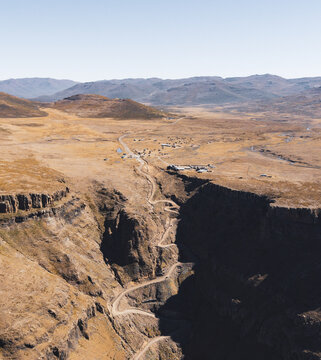 Aerial view of the winding Sani Pass mountain road cutting through the rugged, dry landscape of the Drakensberg mountains in Sani Pass, Lesotho.