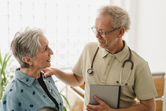 Male doctor comforts female patient during consultation indoors