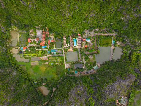 Aerial view of Tam Coc Bich Dong featuring lush green karst mountains surrounding a complex of buildings, ponds, and pathways in Nam Hoa Lu, Ninh Binh, Vietnam.