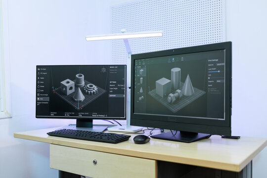 Modern desk setup with dual monitors 3d modeling software and geometric prototypes, ideal for design, engineering and tech work.