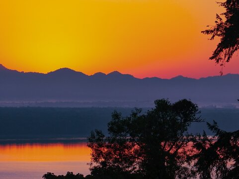 View of the vibrant sunset over the mountains and calm water in Nhila, Teknaf, Cox's Bazar, Chittagong Division, Bangladesh.