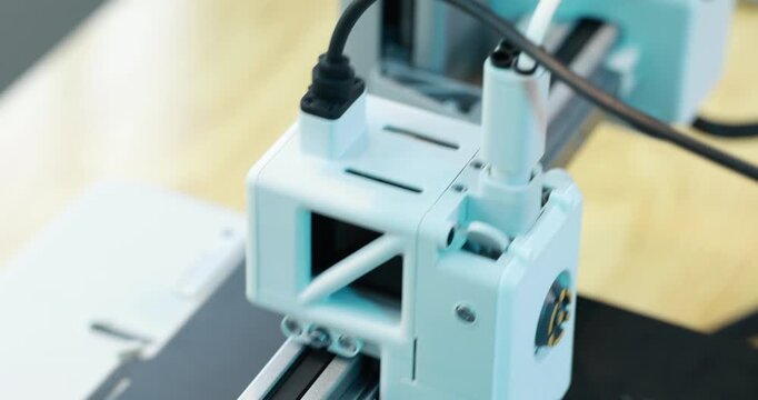 Close-up of a 3d printer head working on a print bed in a modern workshop