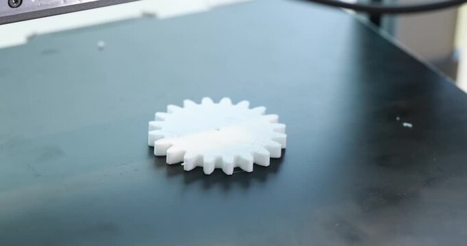 White plastic gear on a dark industrial machine surface, precision manufacturing and product prototyping