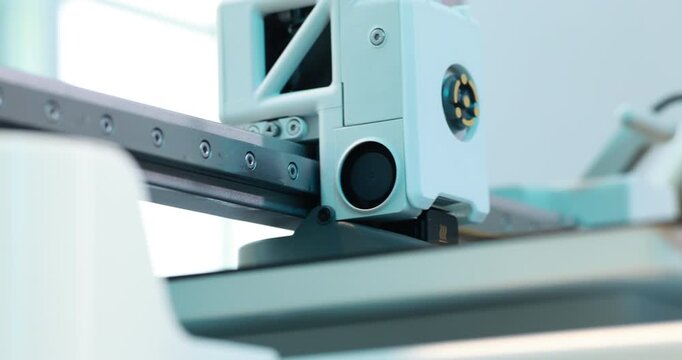Close-up of a 3d printer head moving on a metal rail in a bright workshop