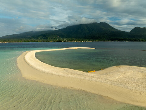 Aerial view of White Island sandbar with a yellow kayak resting on the white sand, surrounded by turquoise waters and distant mountains in Mambajao, Camiguin, Philippines.