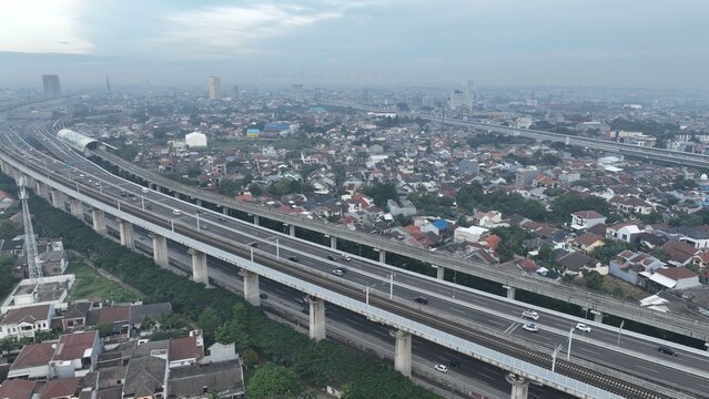 Aerial view of the elevated highway and railway infrastructure winding through the dense urban landscape of Bekasi Barat, West Java, Indonesia.