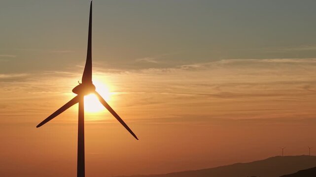 Wind turbine silhouette at orange sunset